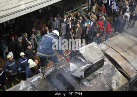 Le Caire, Égypte. Feb 27, 2019. Les pompiers éteignent l'incendie de wagons s'asseoir sur les rails de chemin de fer après un incendie a causé morts et blessés à la gare principale, au Caire. Incendie a éclaté après qu'un train est entré à la station, dépassant la vitesse et entre en collision avec le tampon s'arrêter. Credit : Ahmed Abd Elfatah/dpa/Alamy Live News Banque D'Images