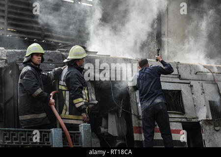 Le Caire, Égypte. Feb 27, 2019. Les pompiers éteignent l'incendie wagons sur la voie ferrée après un incendie a causé morts et blessés à la gare principale, au Caire. Incendie a éclaté après qu'un train est entré à la station, dépassant les limites de vitesse et entre en collision avec le tampon s'arrêter. Credit : Stringer/dpa/Alamy Live News Banque D'Images