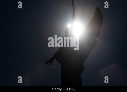 Potsdam, Allemagne. Feb 27, 2019. Un ange figure sur le portail de l'église St Nicolai au vieux marché se distingue comme une silhouette devant le soleil. Credit : Ralf Hirschberger/dpa/Alamy Live News Banque D'Images