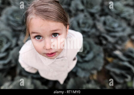 Portrait d'une jeune fille debout sur un champ de choux Banque D'Images