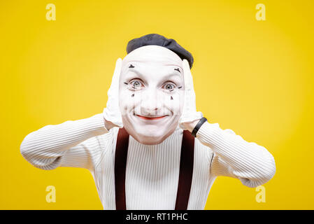 Acteur Pantomime holding facial mask avec émotion positive sur le fond jaune Banque D'Images