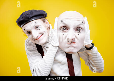 Acteur Pantomime holding facial mask avec les émotions négatives sur le fond jaune Banque D'Images
