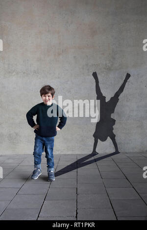Allemagne, Düsseldorf, portrait of smiling little boy et ombre de Duesseldorf est cartwheeler on wall Banque D'Images