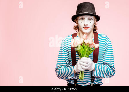 Pantomime émotionnelle posant avec tulip bouquet sur le fond rose à l'intérieur. La Saint-Valentin et l'amour concept Banque D'Images