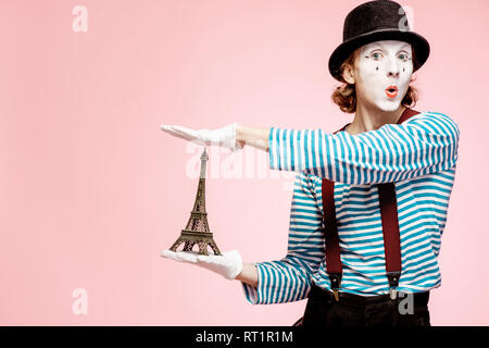 Maquillage du visage blanc avec Pantomime posant avec Tour Eiffel sur le fond rose. Concept mime français Banque D'Images
