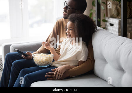 L'Afrique de l'heureux père de famille avec enfant fille regarder la télévision ensemble Banque D'Images