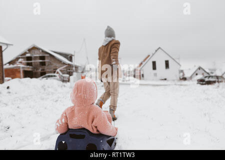 Boy pulling sled avec petite soeur dans la neige Banque D'Images