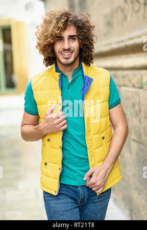 Portrait de jeune homme avec les cheveux bouclés portant Gilet jaune à l'extérieur Banque D'Images