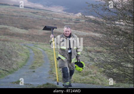 Un pompier fait sa façon de s'attaquer à la forêt sur Saddleworth Moor dans le West Yorkshire. Une zone d'environ 1,5 kilomètres carrés a été brûler après la Grande-Bretagne a vu son jour de l'hiver le plus chaud jamais enregistré, mardi. Banque D'Images