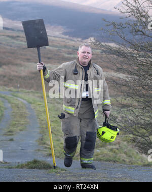 Un pompier fait sa façon de s'attaquer à la forêt sur Saddleworth Moor dans le West Yorkshire. Une zone d'environ 1,5 kilomètres carrés a été brûler après la Grande-Bretagne a vu son jour de l'hiver le plus chaud jamais enregistré, mardi. Banque D'Images