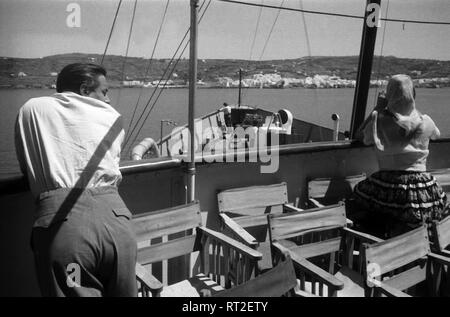 France, Grèce - Ein Mann und eine Frau stehen an der Reling votre Kreuzfahrtschiffes genießen und die Aussicht auf die Küste, Griechenland, 1950er Jahre. Un homme et une femme s'apprécier la vue de leur bateau de croisière de la côte, Grèce, 1950. Banque D'Images