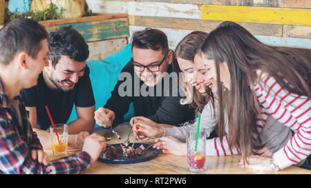 Happy friends partager tranche de gâteau au parti pub Banque D'Images