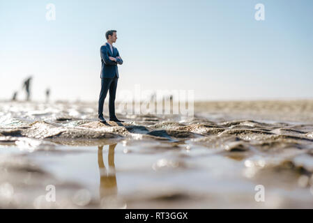 Figurine homme debout sur la plage humide, à la recherche à distance Banque D'Images