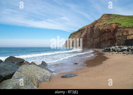 Plage de sable fin et hautes falaises à Skinningrove sur la côte de North Yorkshire, Angleterre. Partie de la Cleveland Way. Banque D'Images