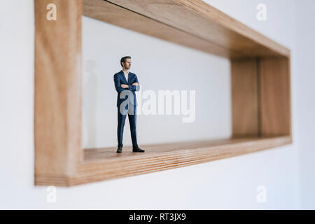 Figurine homme debout dans le cadre en bois avec les bras croisés Banque D'Images