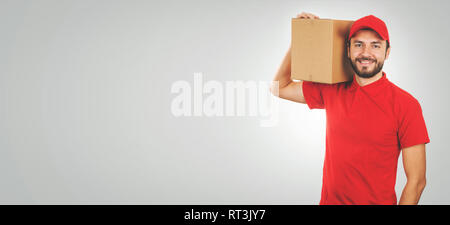 Young smiling man en uniforme rouge et avec l'expédition fort sur l'épaule. copy space Banque D'Images