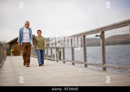 Portrait d'un jeune garçon marchant le long d'un quai avec son grand-père. Banque D'Images