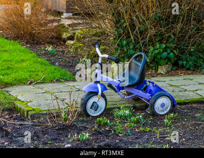 Tricycle garé dans le jardin, des jouets pour enfants, jouets pour enfants populaires Banque D'Images