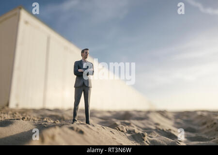 Figurine homme debout sur le sable en face du bâtiment Banque D'Images