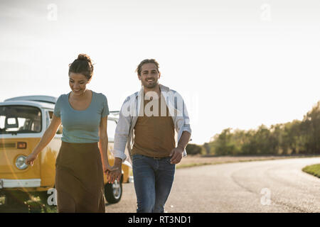 Couple heureux de faire un voyage sur la route avec un camping-car, tenant la main sur la route Banque D'Images