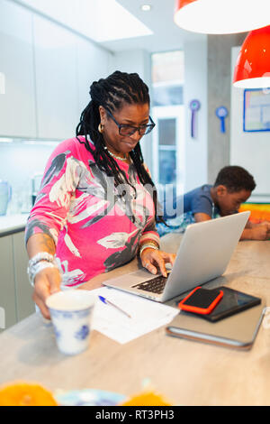 Mature Woman using laptop in kitchen Banque D'Images