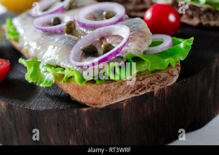 Filet de hareng avec sel, poivre, herbes, l'oignon et de citron sur la plaque noire sur fond blanc. Vue de dessus de la nourriture saine. Banque D'Images