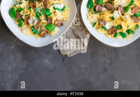 Pâtes farfalle fraîches maison aux champignons et épinards sur fond de béton. Vue d'en haut. Banque D'Images