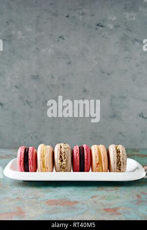 Assortiment de macarons français des gâteaux sur un plat rectangulaire sur un fond gris. Petits gâteaux colorés français. Vue d'en haut. Banque D'Images