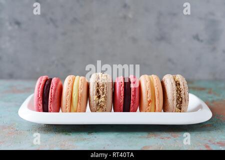 Assortiment de macarons français des gâteaux sur un plat rectangulaire sur un fond gris. Petits gâteaux colorés français. Vue d'en haut. Banque D'Images