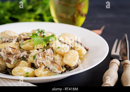 Gnocchi à la crème de persil et la sauce dans un bol sur un fond sombre Banque D'Images