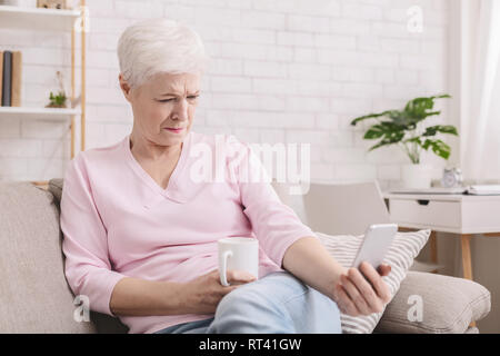 Senior woman avec des problèmes de vision à l'aide de Phone Banque D'Images