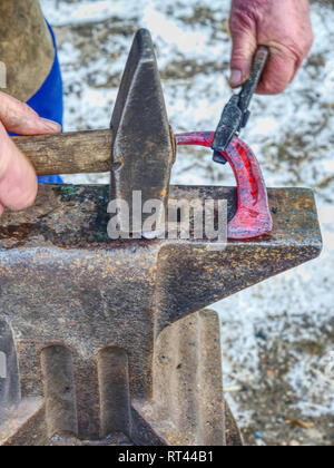 Forgeron forge sex horseshoe. Maréchal-ferrant est de frapper avec un marteau en fer à cheval sur l'enclume Banque D'Images