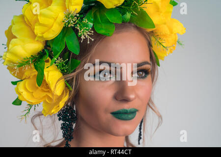 Close-up face à une belle jeune fille avec un miroir lumineux et de grandes fleurs jaunes sur la tête. Banque D'Images