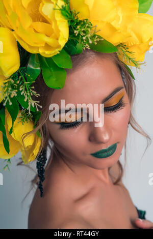 Close-up face à une belle jeune fille avec un miroir lumineux et de grandes fleurs jaunes sur la tête. Banque D'Images