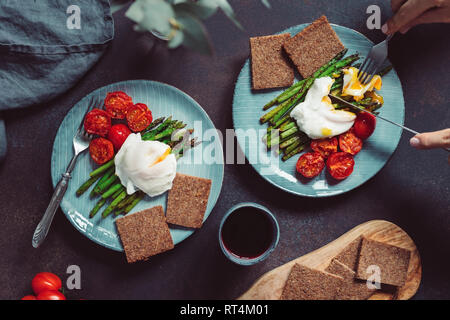 Vue de dessus sur un dîner pour deux personnes, œuf poché sur grill les asperges et tomates cerises. Banque D'Images