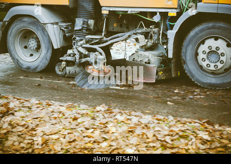 Détail de roues en mouvement orange street sweeper truck sur la rue nettoyage de feuillage de l'automne Banque D'Images