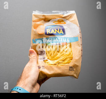 PARIS, FRANCE - NOV 26, 2017 : Man hand holding contre l'arrière-plan gris un sac de produits frais prêts à cuire des nouilles faites par RANA Banque D'Images