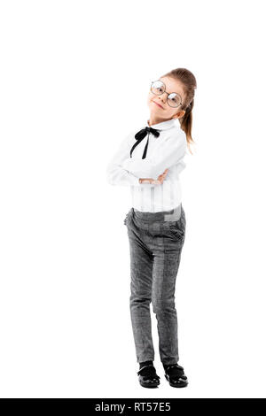 Belle petite fille habillée comme une fille de l'école - en chemise blanche et un pantalon gris, lunettes rondes debout près de mur blanc et de poser comme modèle. Banque D'Images