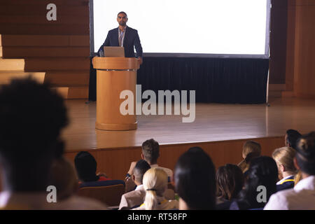 Businessman standing autour de la tribune et de donner la parole à l'avant de l'auditoire dans l'auditorium Banque D'Images