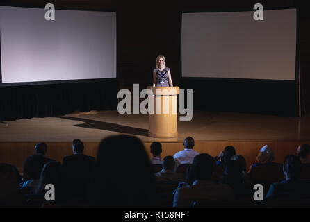 Businesswoman standing autour de podium et présentation donnant à l'auditoire Banque D'Images