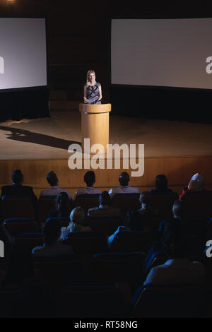 Businesswoman standing autour de podium et présentation donnant à l'auditoire Banque D'Images