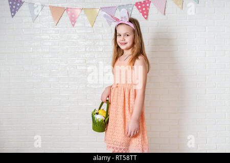 Happy cute girl wearing Bunny Ears et avec des décorations de Pâques sur fond blanc Banque D'Images