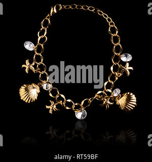 Collier coquillage or isolé sur fond noir Banque D'Images