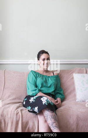 Portrait smiling woman, avec des tatouages sur le sofa du salon Banque D'Images