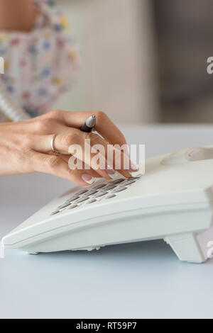Image main de femme libre de composer le numéro de téléphone à l'aide de téléphone fixe blanc. Banque D'Images