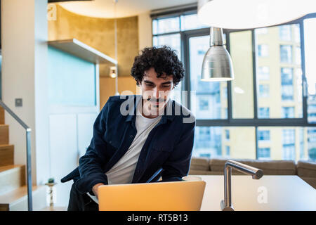 Focused man working at laptop dans la cuisine de l'appartement Banque D'Images