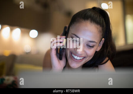 Happy Woman talking on smart phone at laptop Banque D'Images