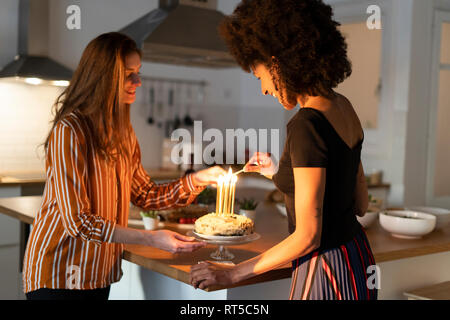 La préparation d'amis birtday gâteau avec bougies allumées comme surprise Banque D'Images