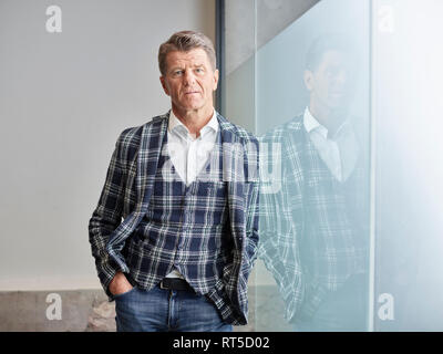 Portrait of businessman leaning against glass wall Banque D'Images