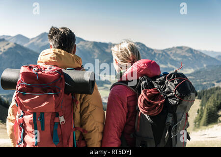 Autriche, Tyrol, vue arrière du couple en randonnée dans les montagnes en profitant de la vue Banque D'Images